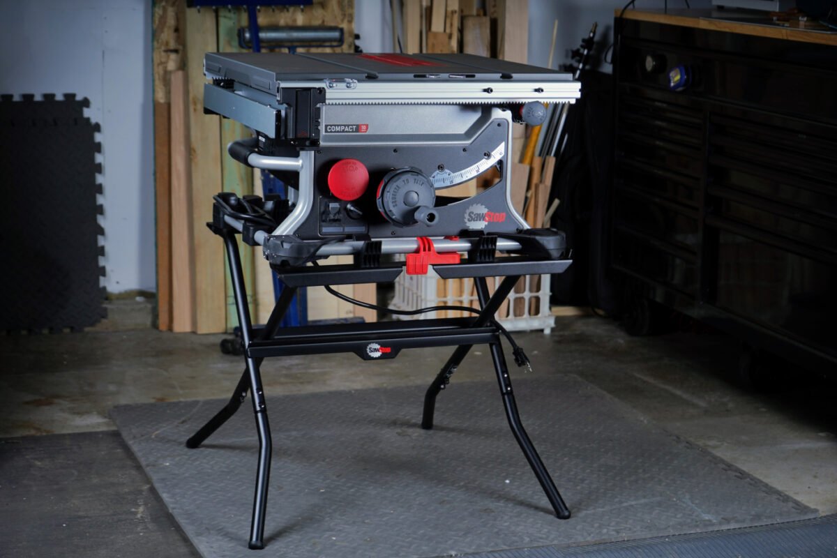 A woodworker operating the SawStop Compact Table Saw, making a precise cut on a piece of wood, demonstrating its use in a real-world woodworking project.