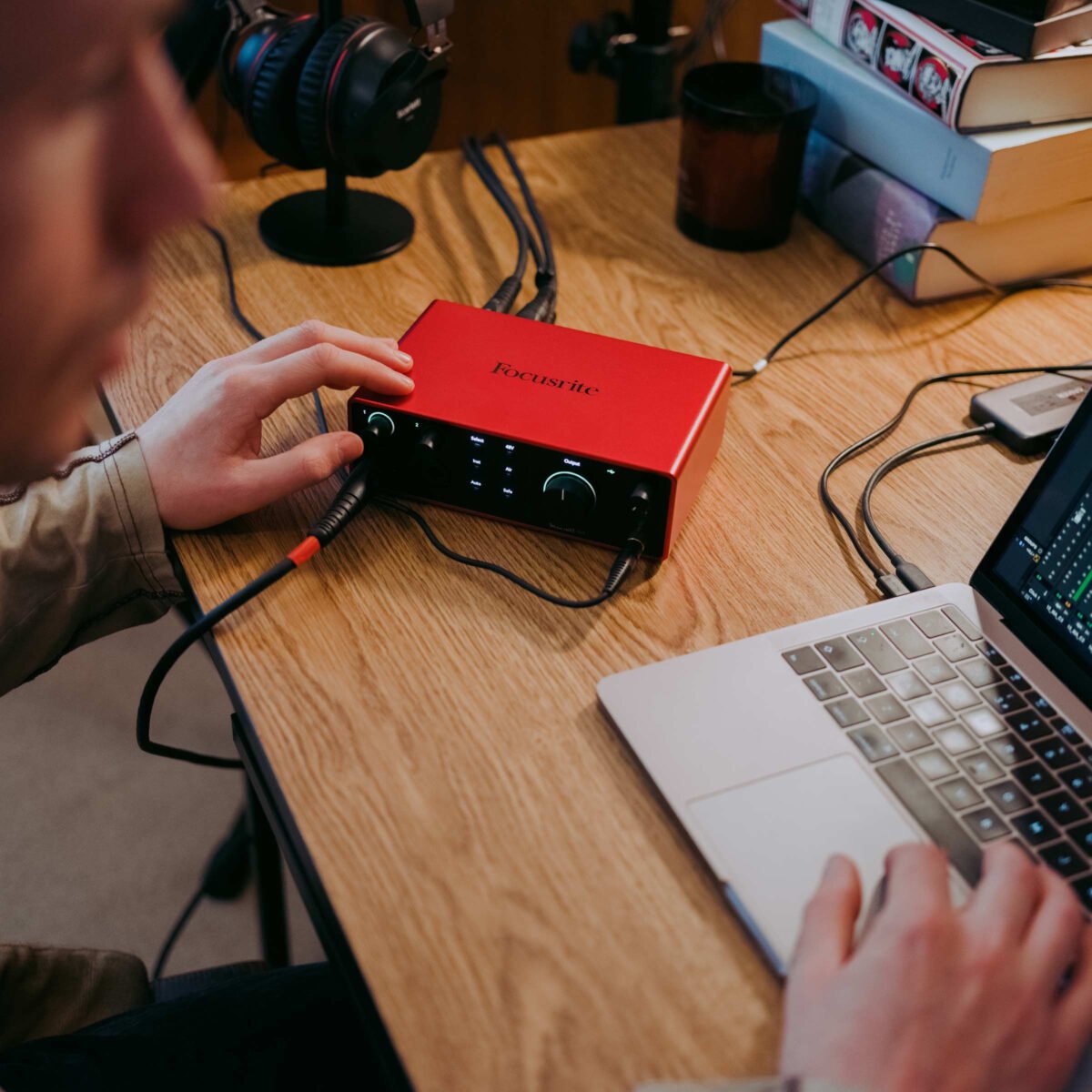 A Focusrite Scarlett 4i4 4th Gen audio interface integrated into a home studio setup, with headphones and a microphone connected, demonstrating its use for music production and content creation.